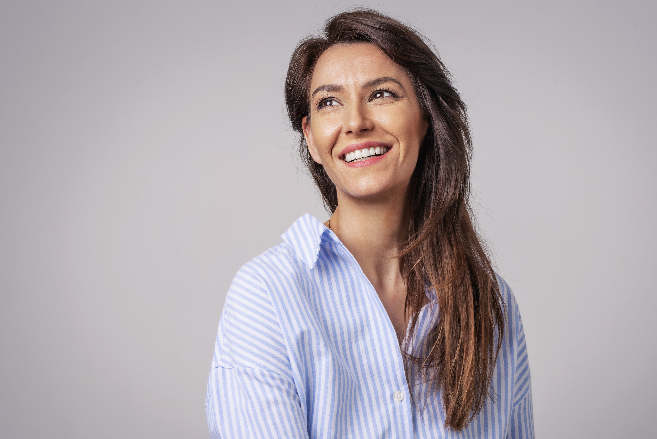 Brown haired woman smiling in a blue striped blouse