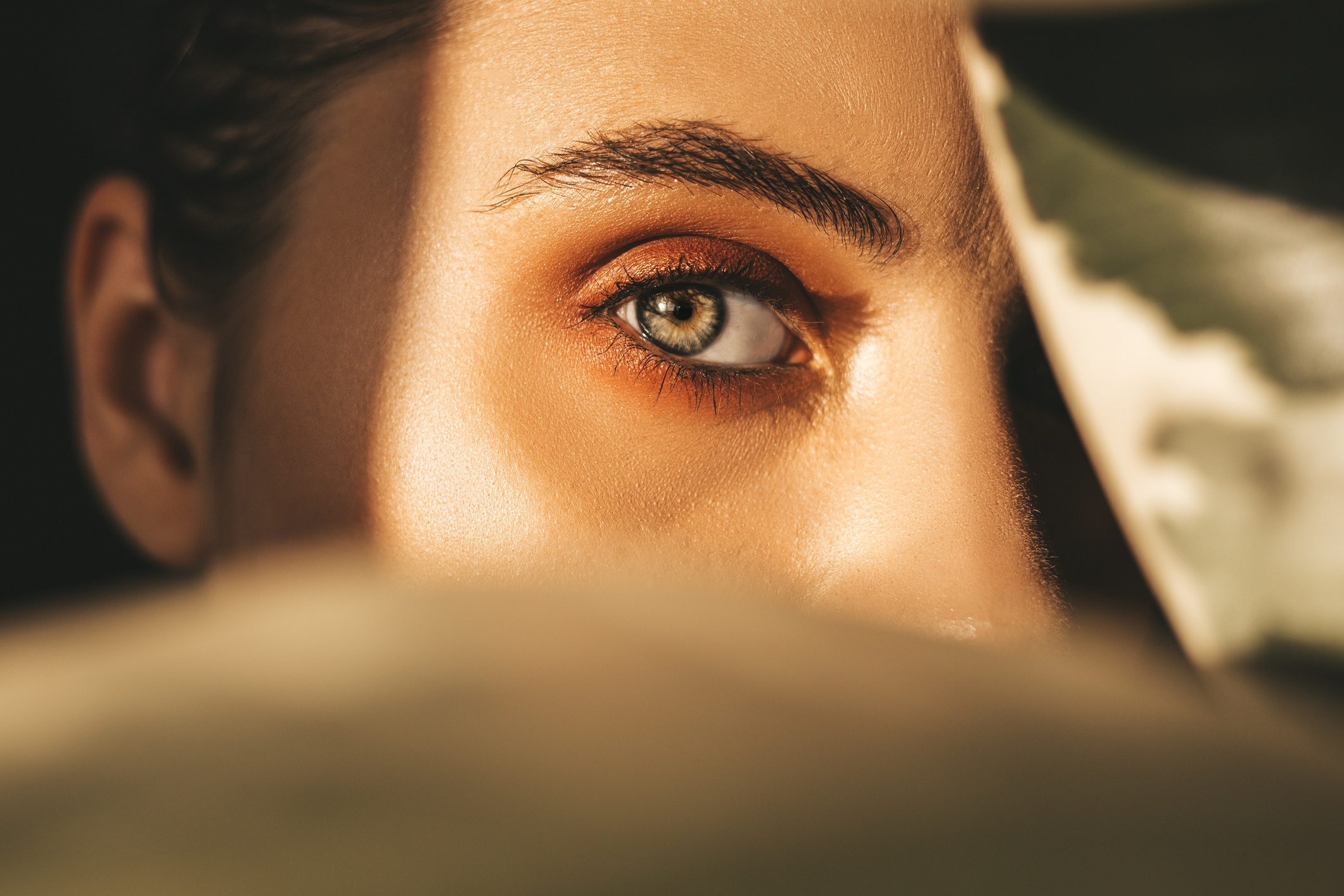 woman hiding behind a leaf with her eye showing