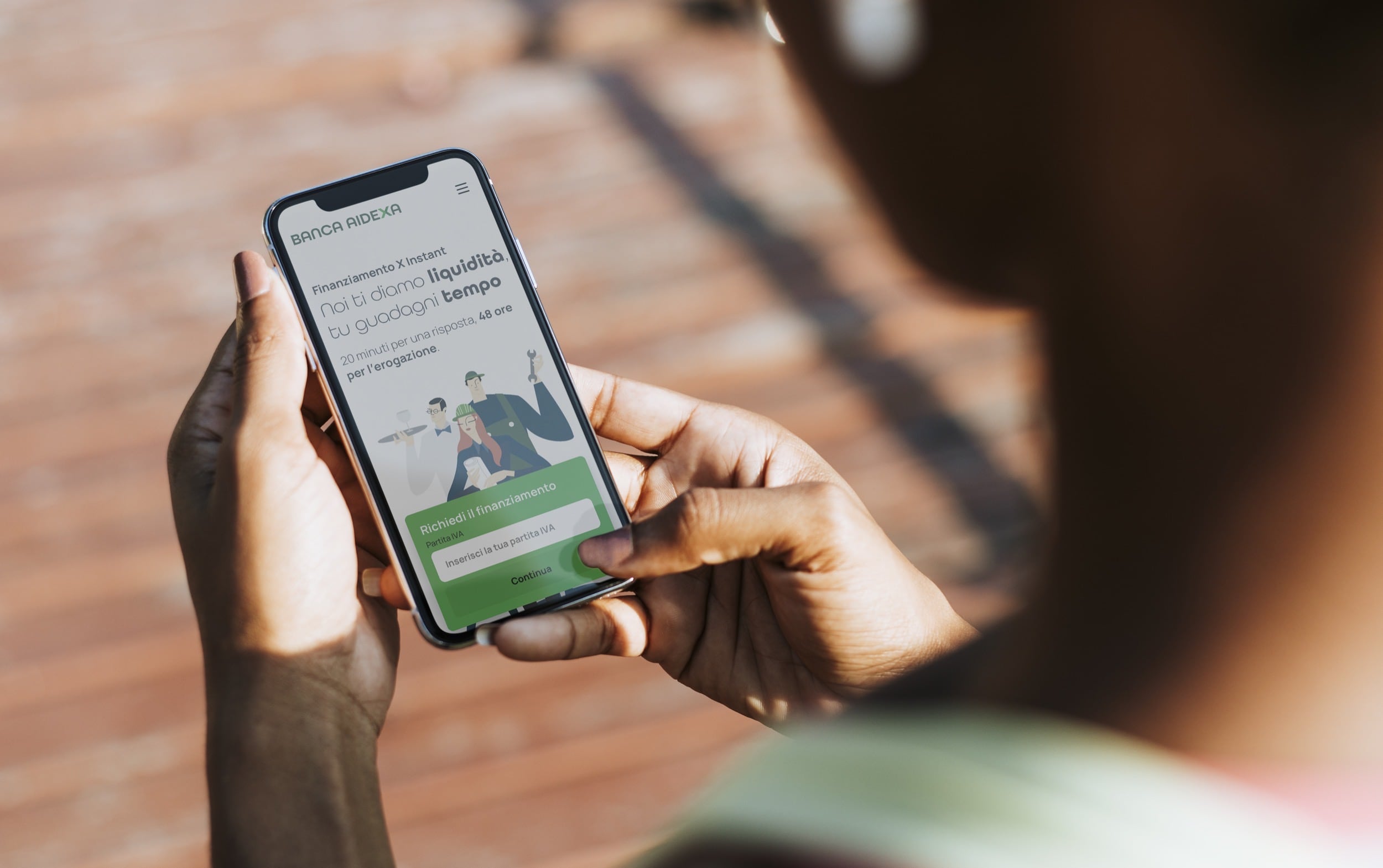 An hand holding a smartphone that shows Banca AideXa's Corporate Website home page