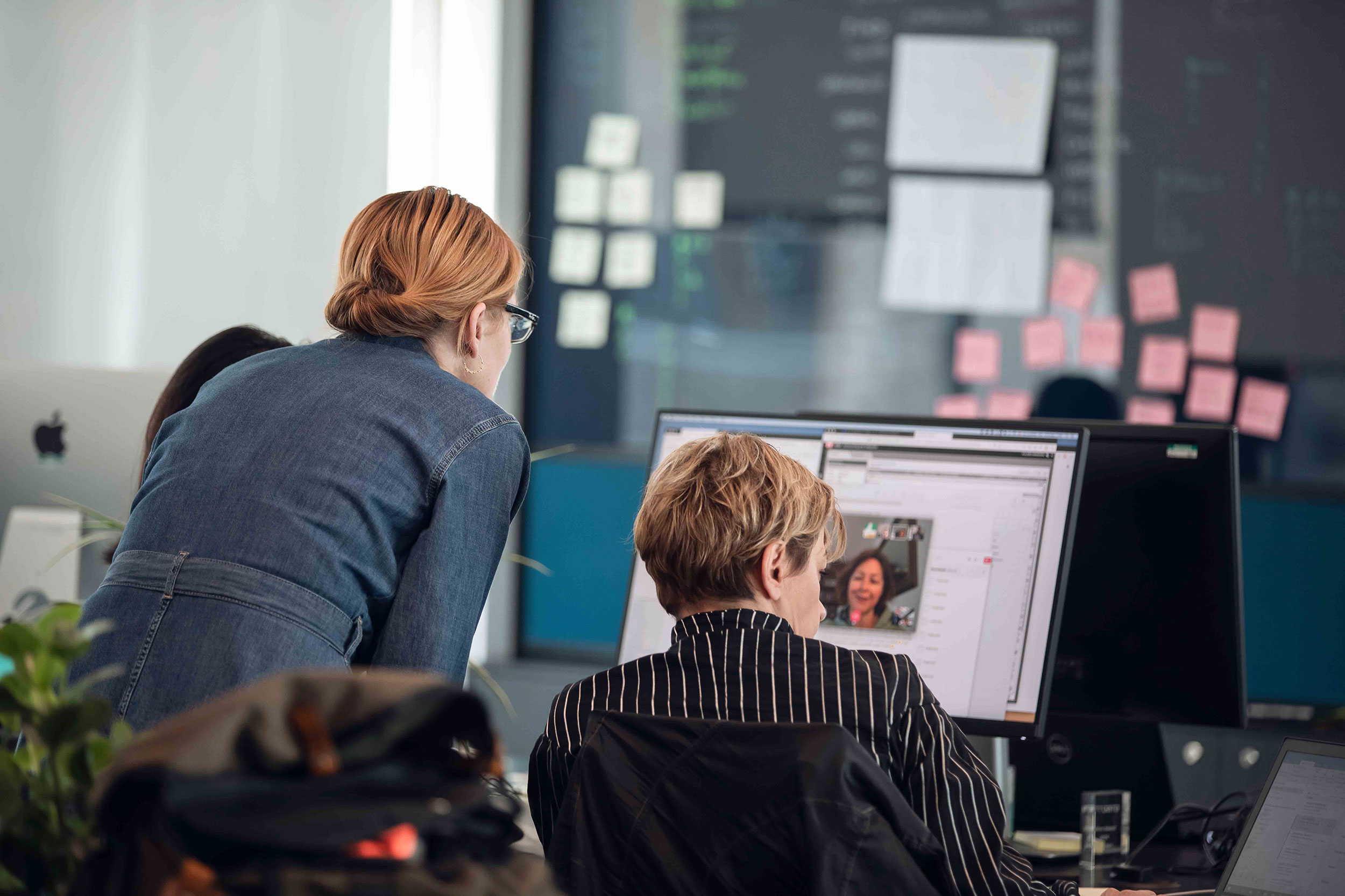 Two people at their desk participating in a virtual meeting.