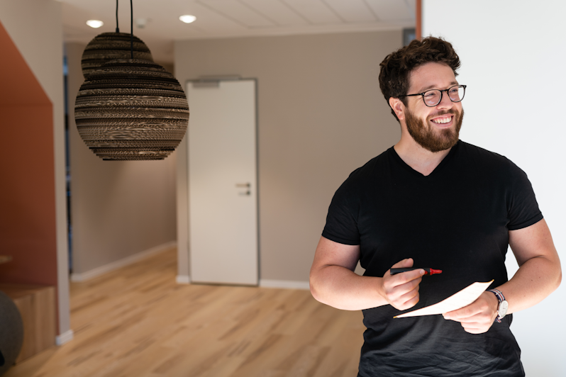 A person smiles while taking notes during a meeting