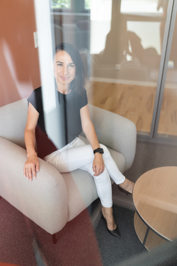 A person sitting in an armchair inside the study, reflected through the glass