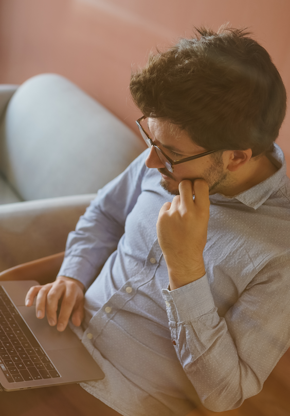 A designer works with their laptop while sitting on one of the sofas in the studio