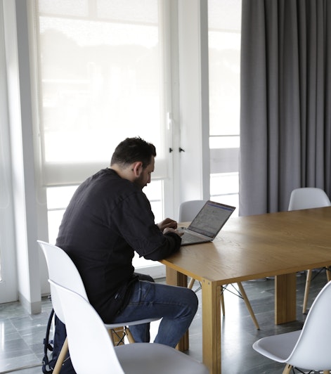 A person works with his laptop on a large table in the meeting room
