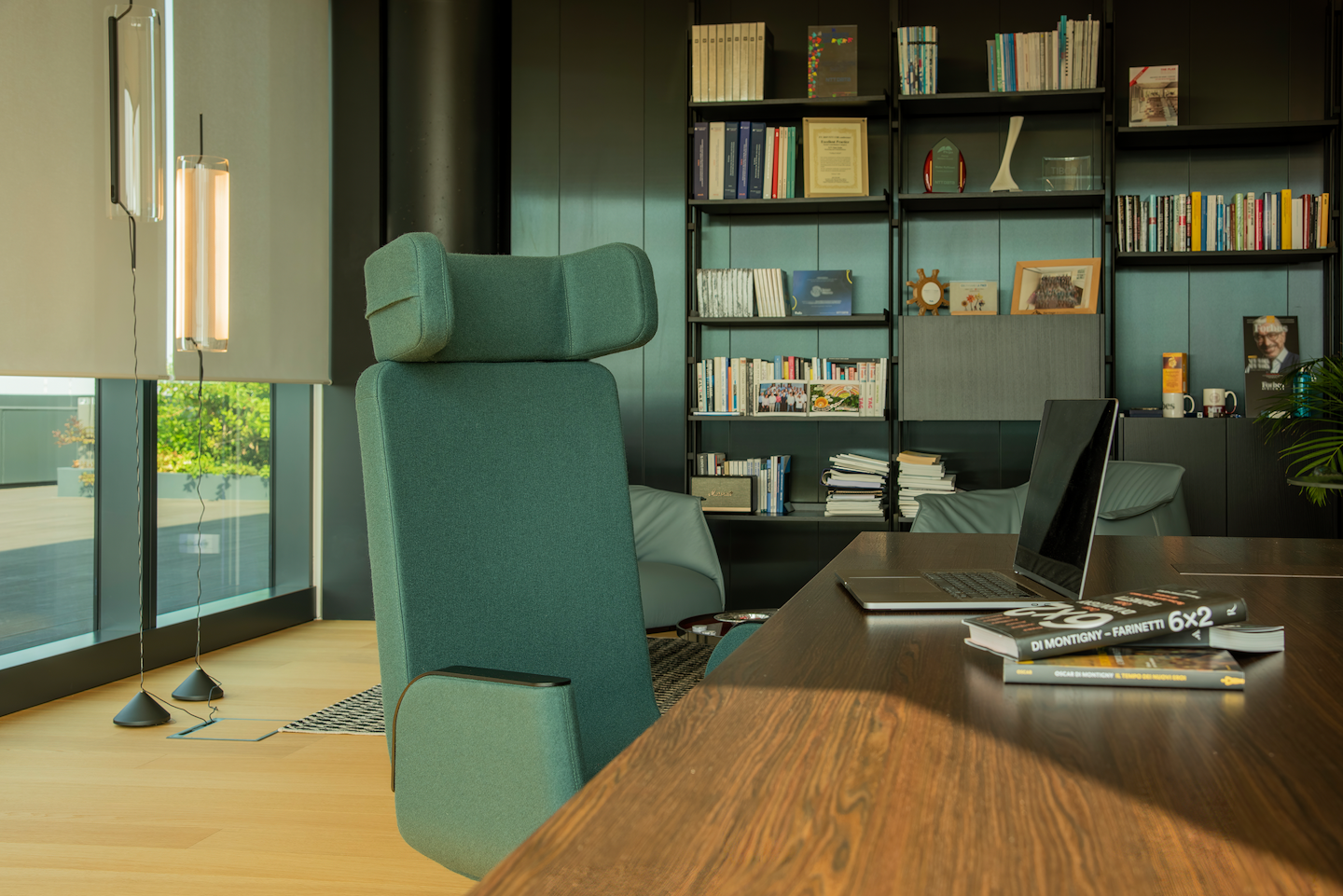 Green Silente chair at the office with laptop on desk and library in the background
