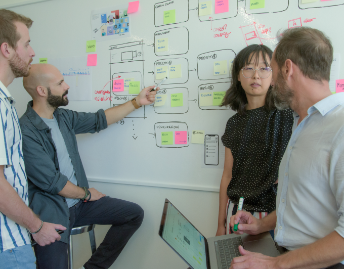 Four designers discussing with each other infront of white board.