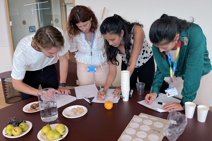 Designers writing standing around table with food