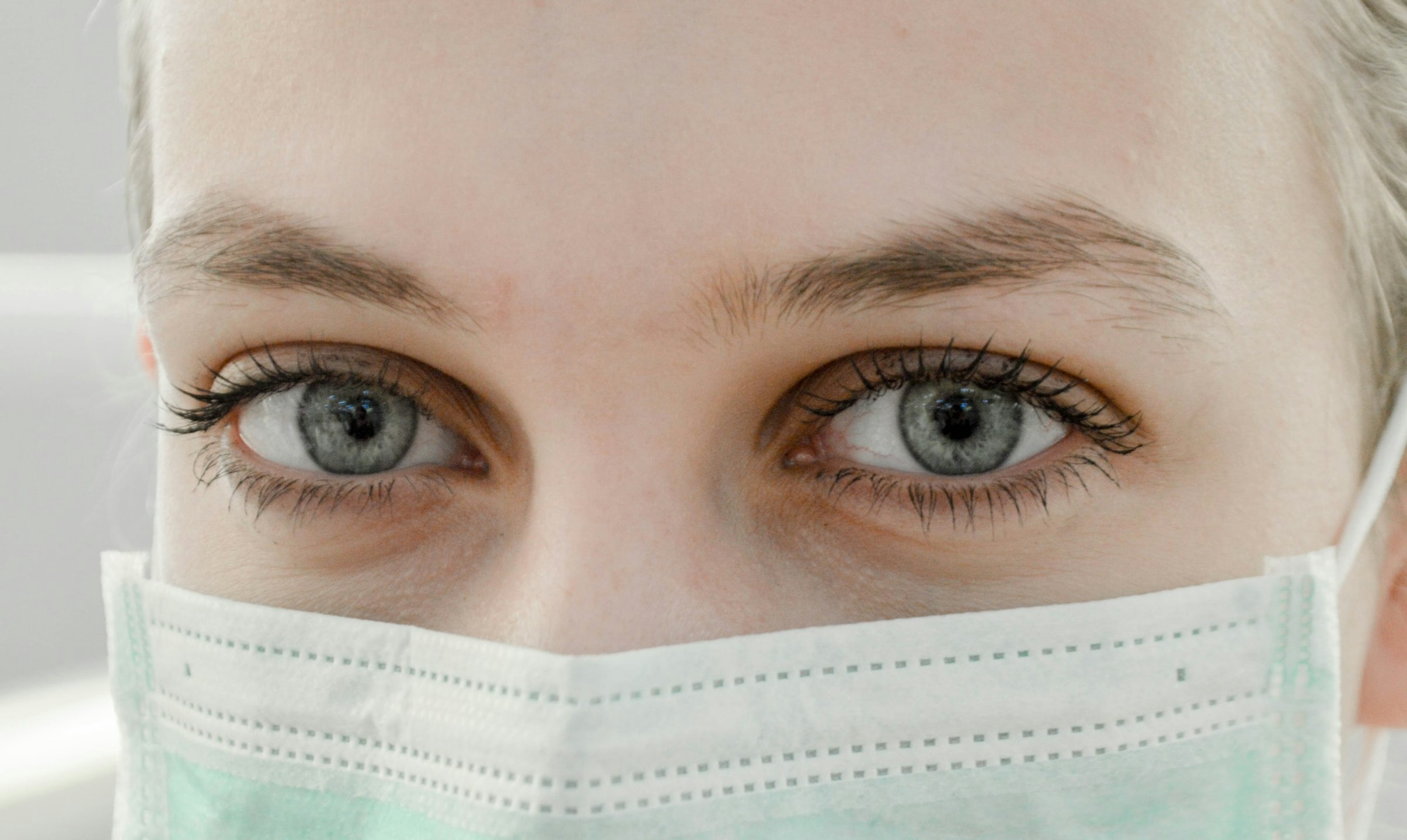 Close up of woman with blue eyes wearing a face mask