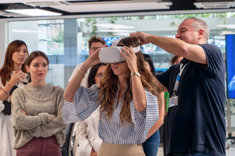 Girl trying the new VR experience surrounded by her colleagues in a IOT showroom