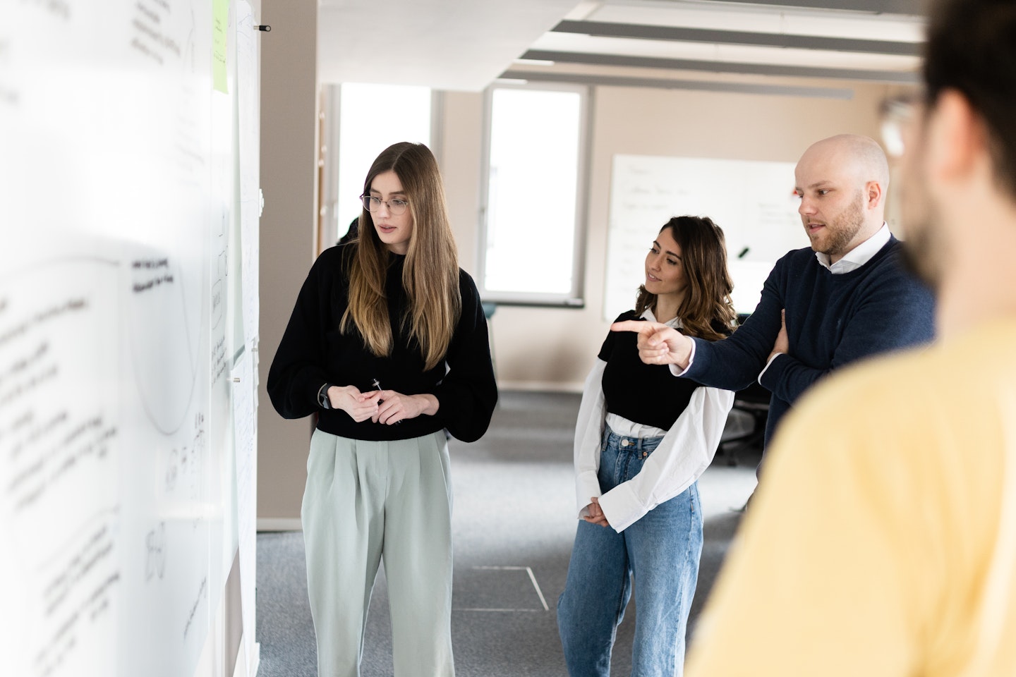 Three Tangity team members collecting and selecting ideas on a whiteboard.