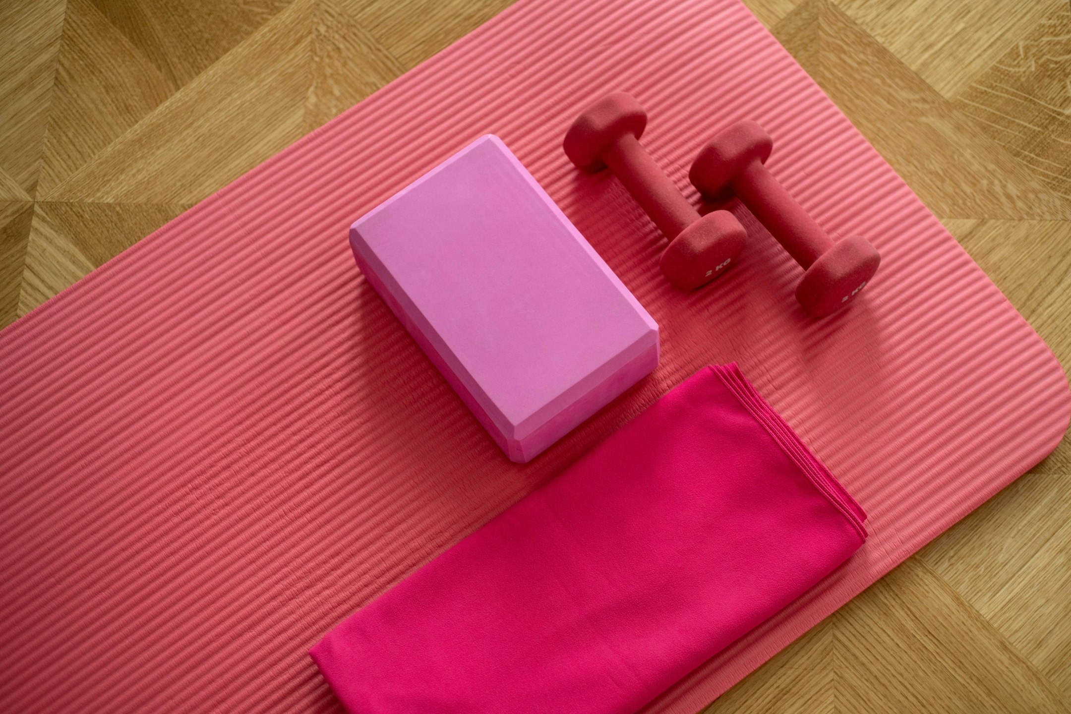 Pink yoga mat with block, dumb bells and towel