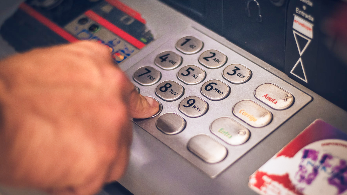 Finger pressing on number 0 on ATM machine