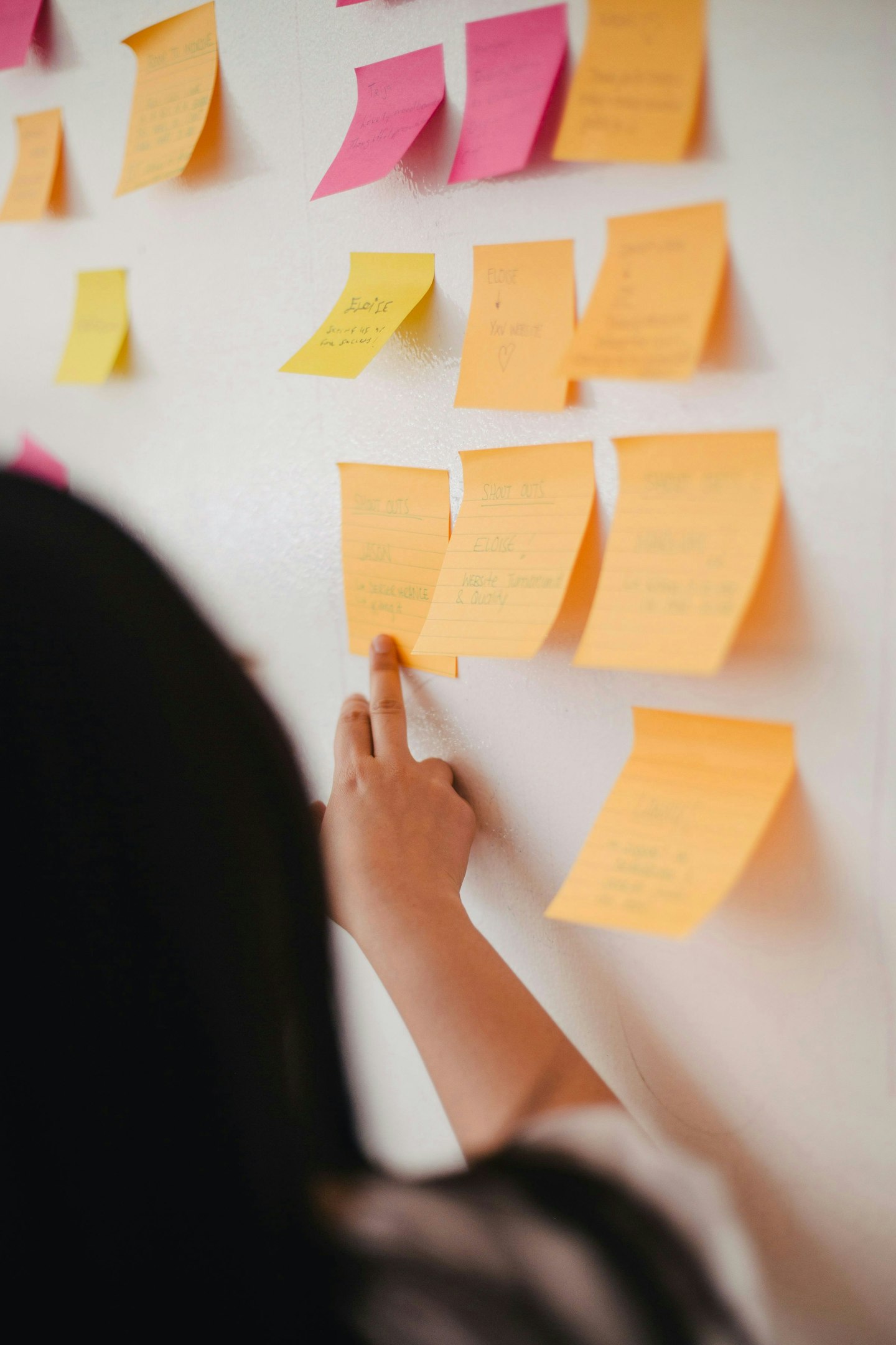 Peroson pointing on an orange post-it on the wall