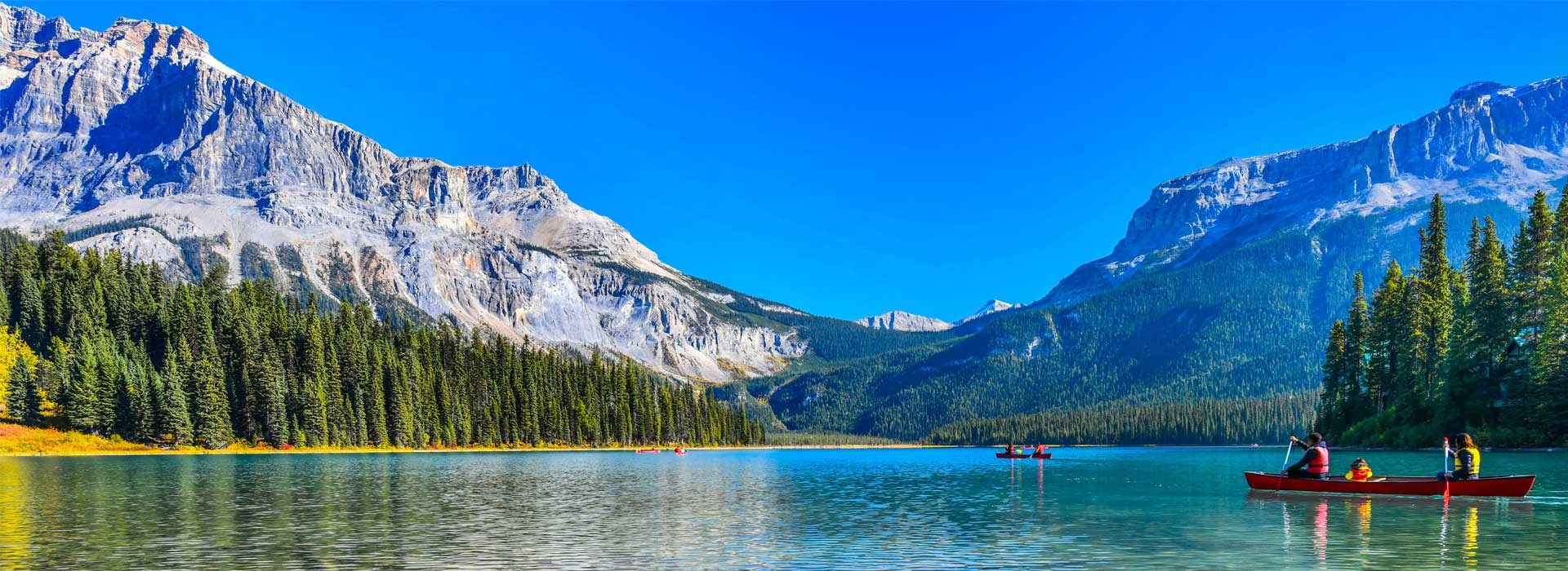 canoeing in lake surrounded by forests and mountains