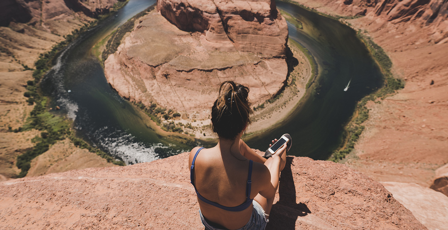 Woman sitting on cliff looking at canyon river