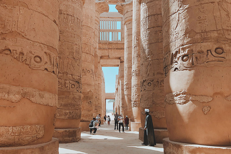 Tourists view tall columns of egyptian ruins