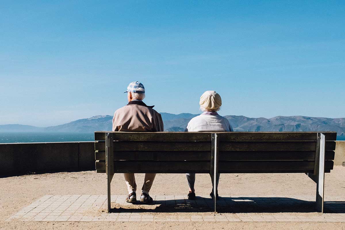 Two seniors sitting on bench enjoying view