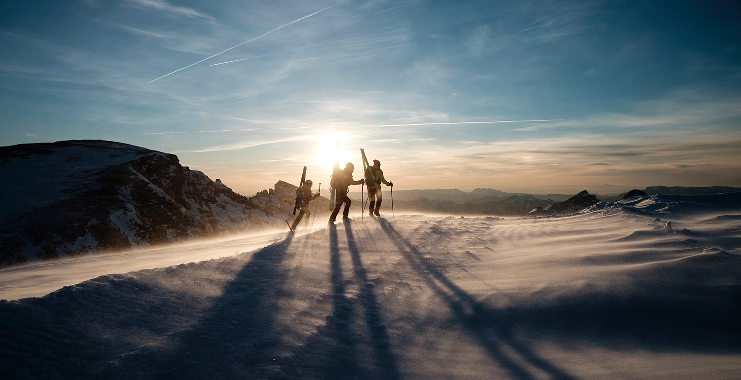 Three people hiking in snow covered mountains