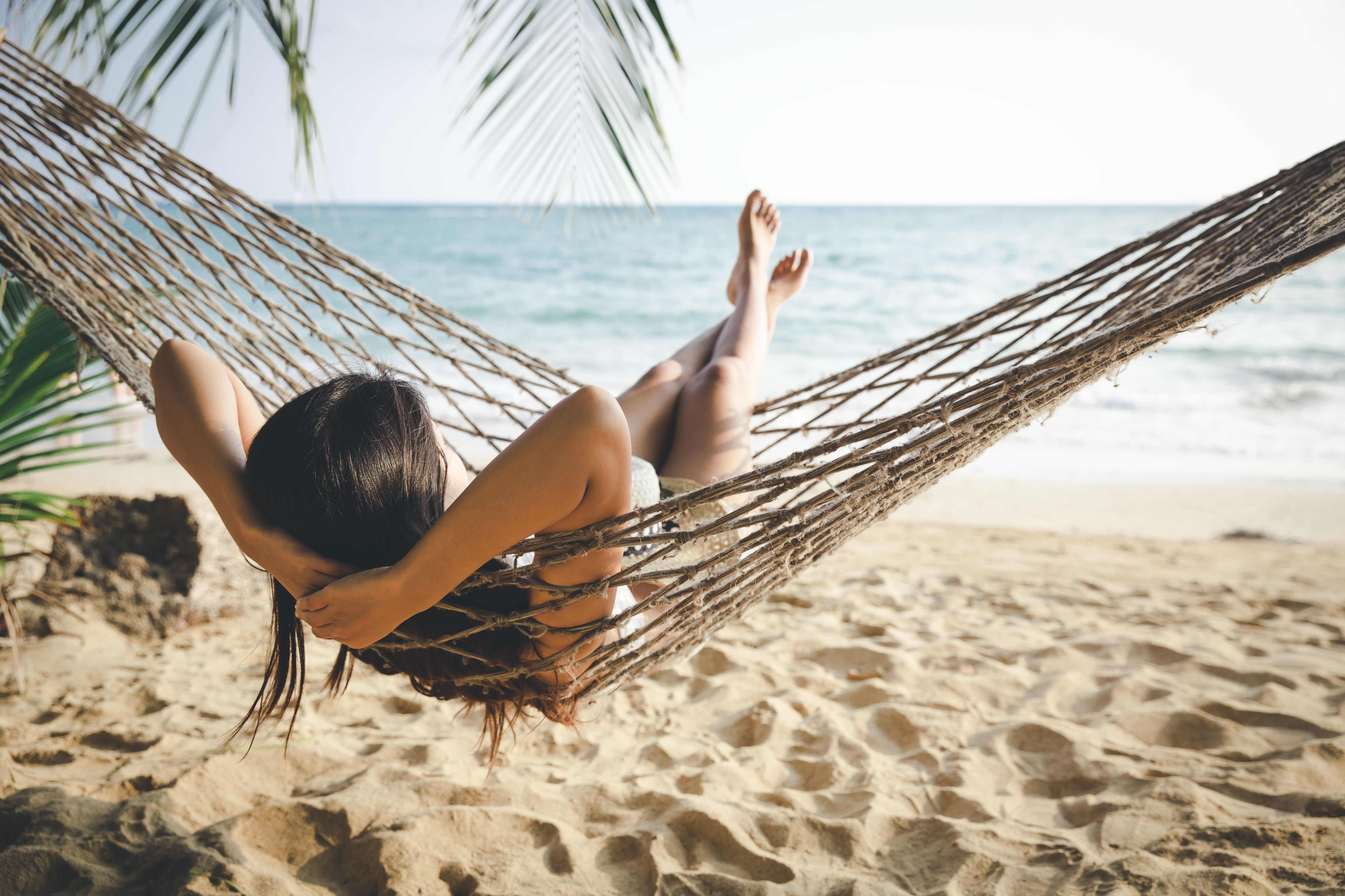 Woman relaxing in hammok on beach