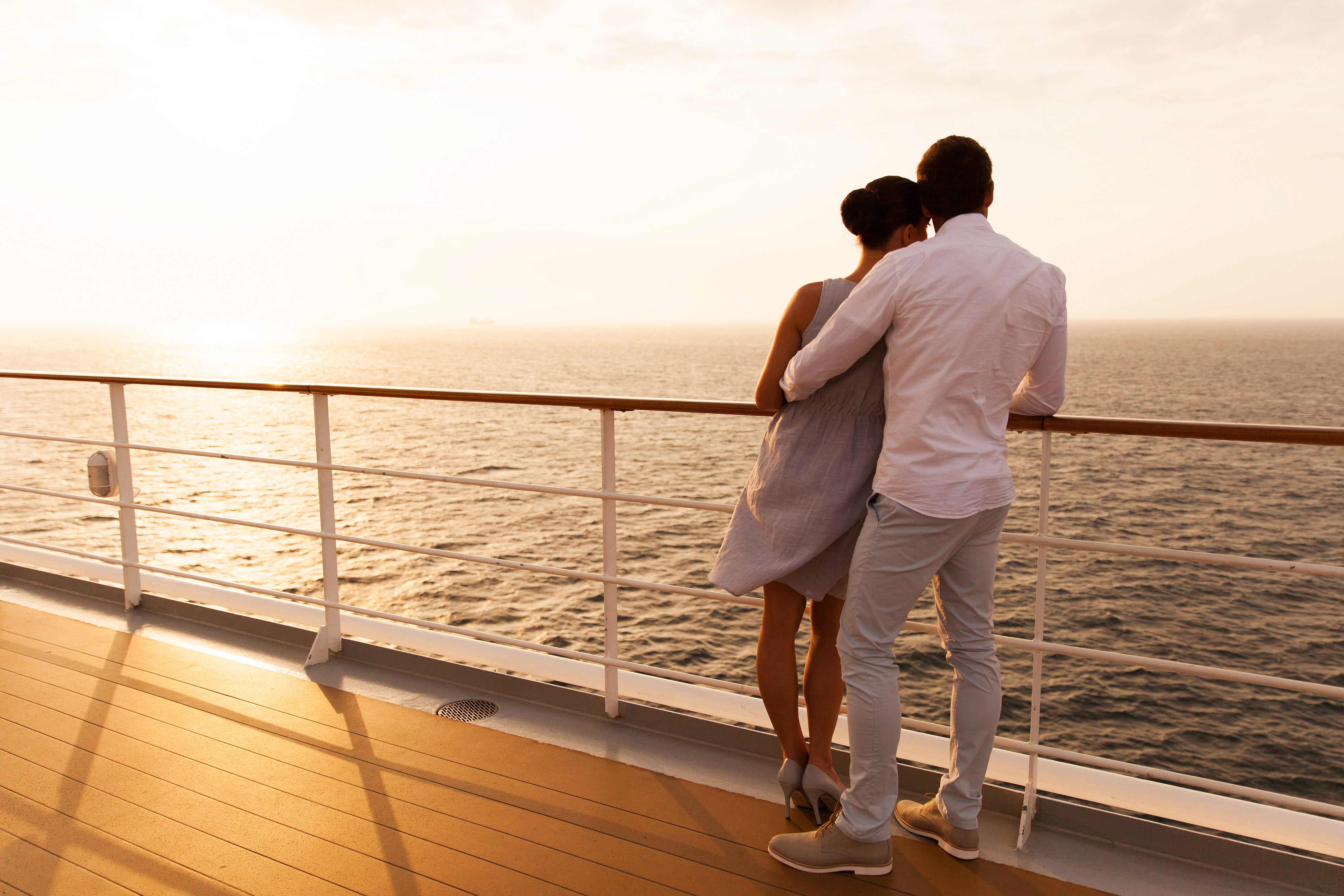Couple on ship deck watching sunset