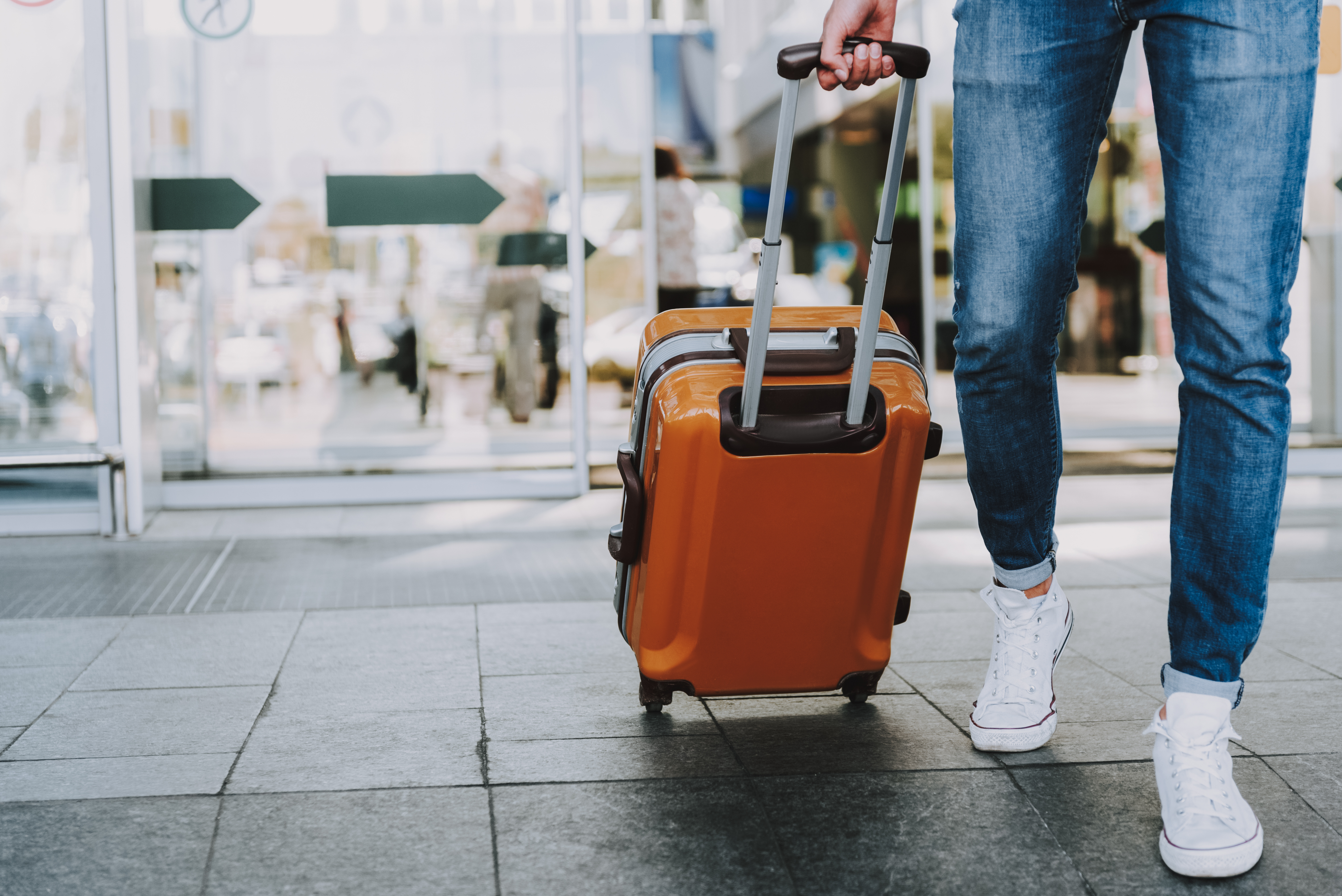 Person pulling suitcase through sliding doors