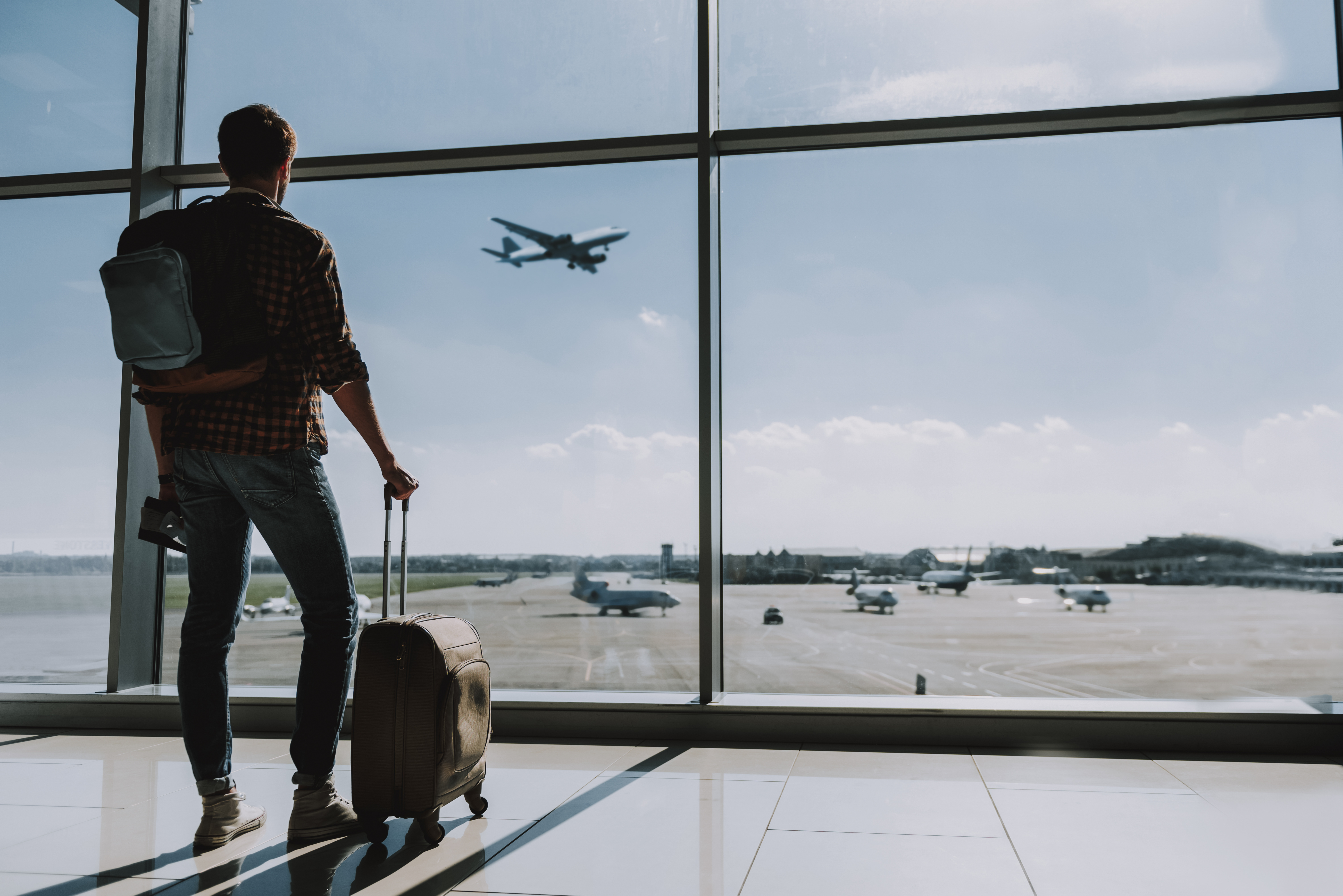 Man watching plane take off through airport window