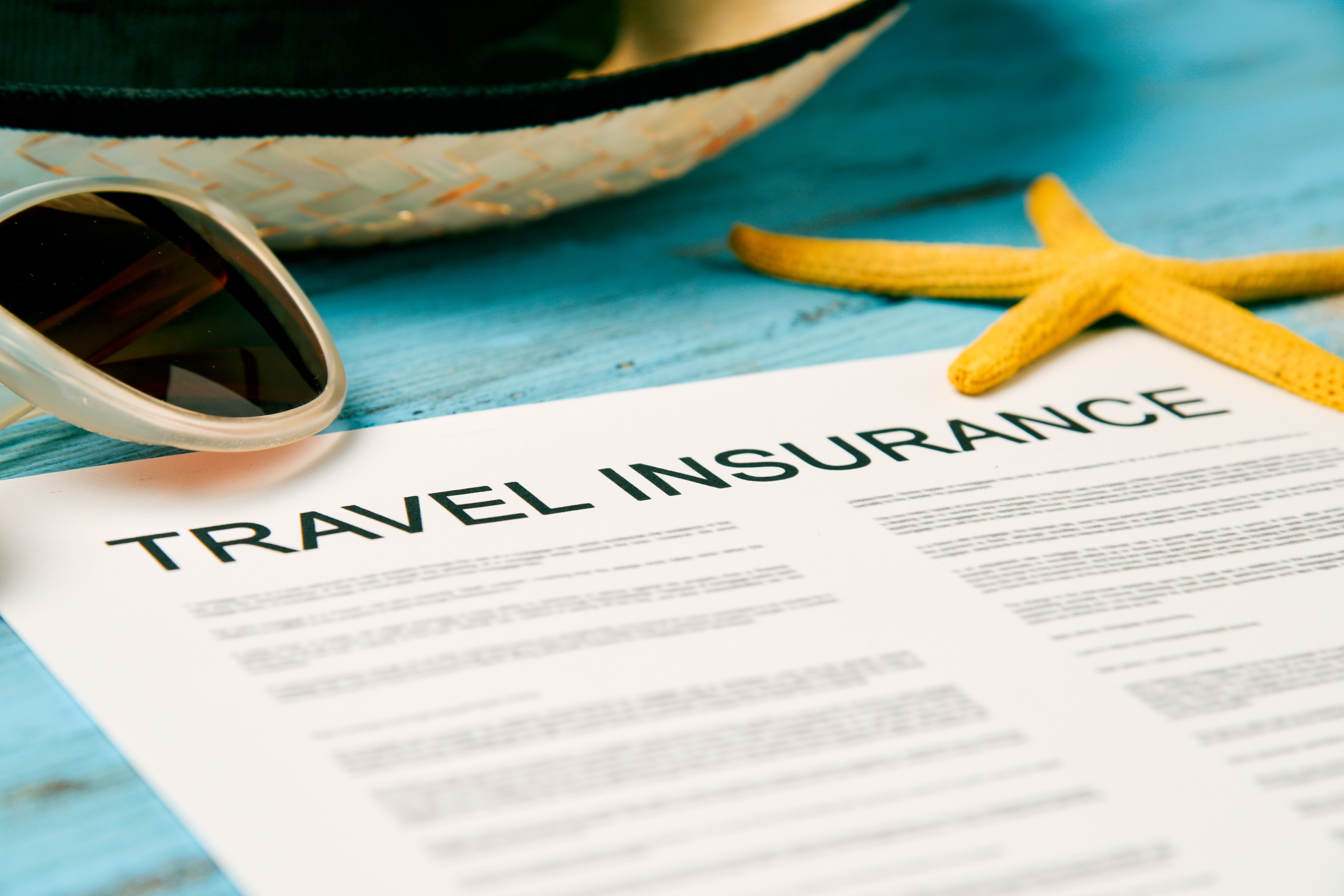 Travel insurance policy next to starfish and sunglasses