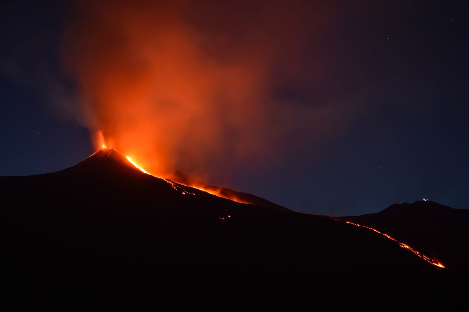 Active volcano erupting at night