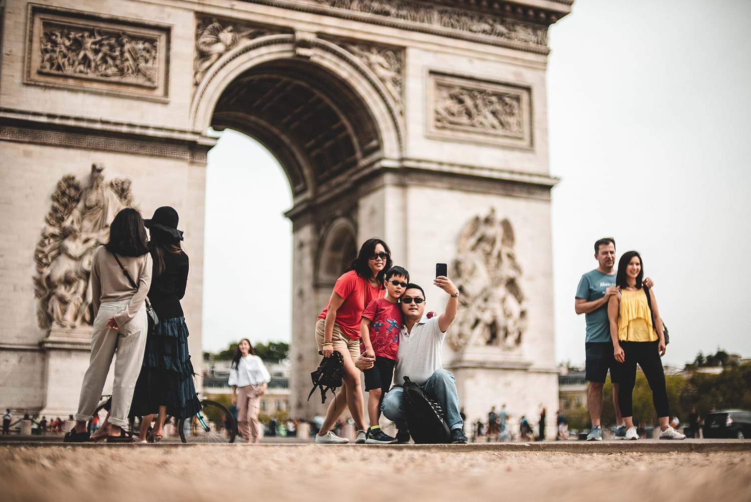 Tourists taking photos at the Arc de Triomphe in Paris