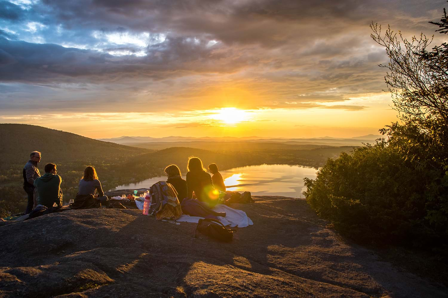 Group picknicking on cliff watching sunrise