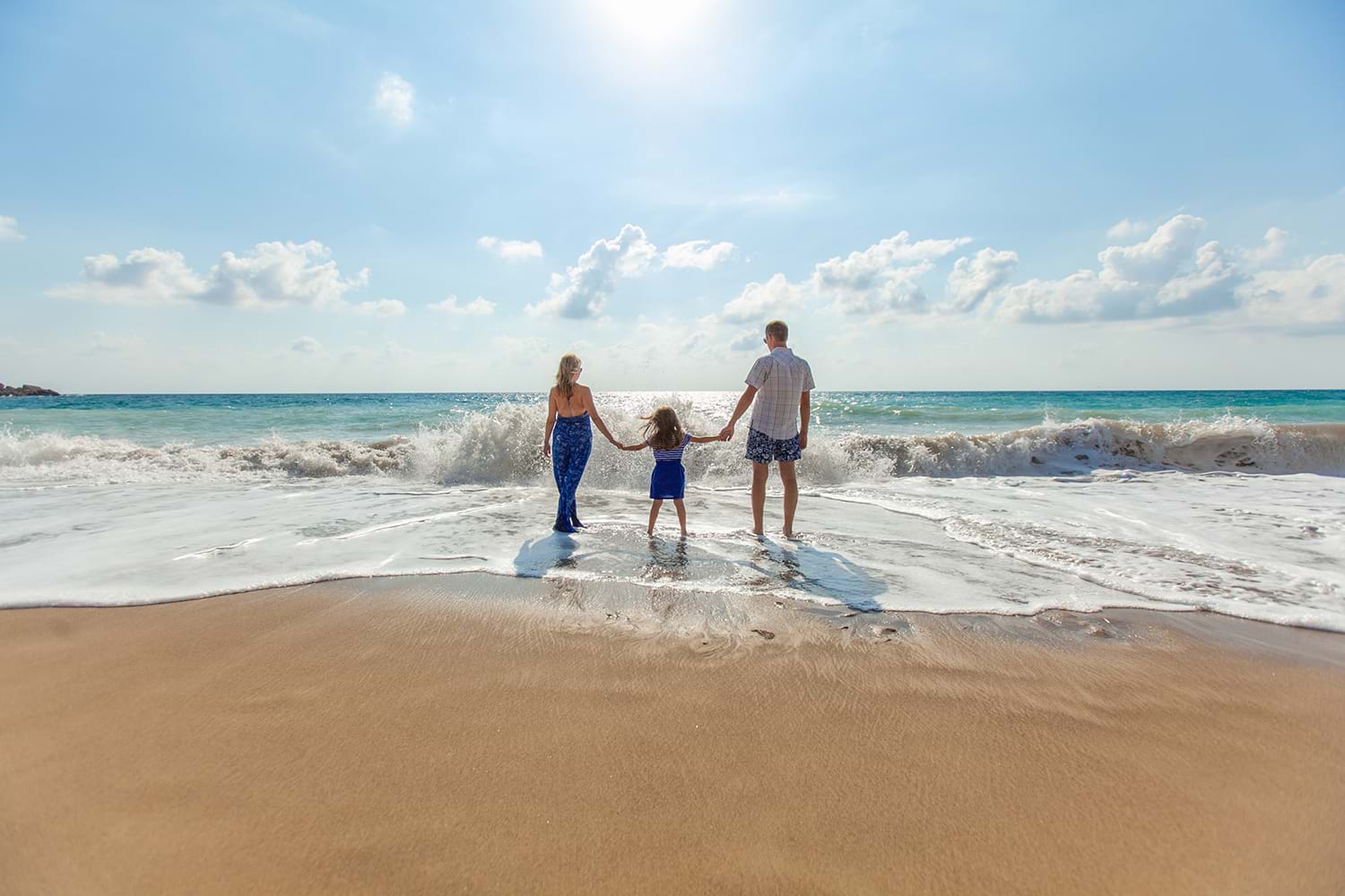 Family standing in waves at a beach