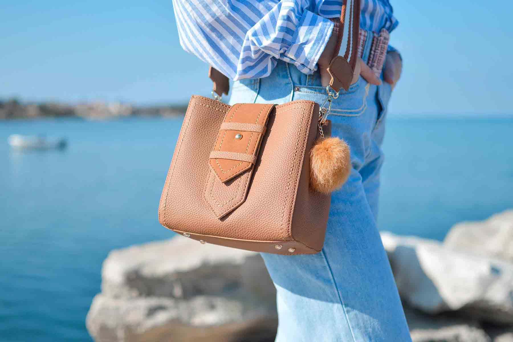 Person with brown purse by water