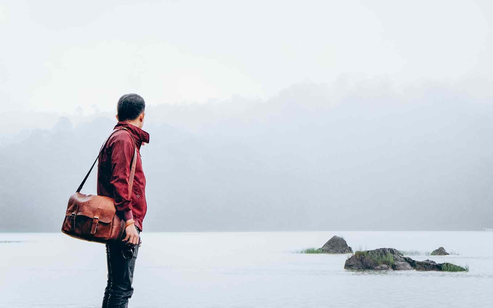 Man looking out over water covered by fog