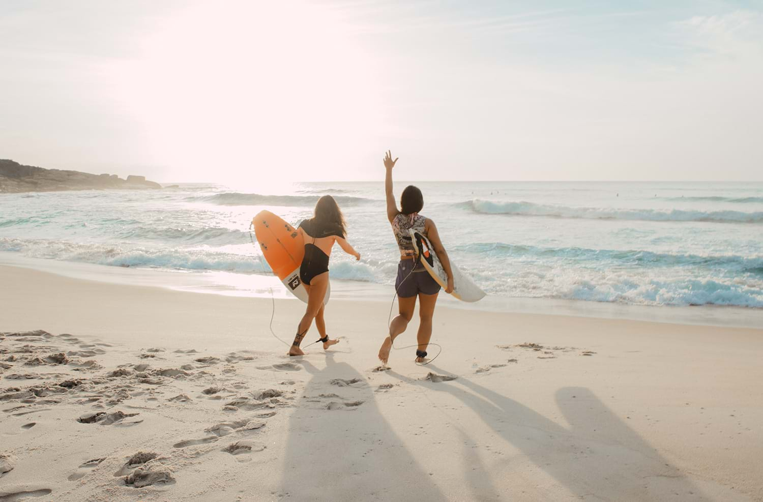 Two surfers walking on the beach towards water