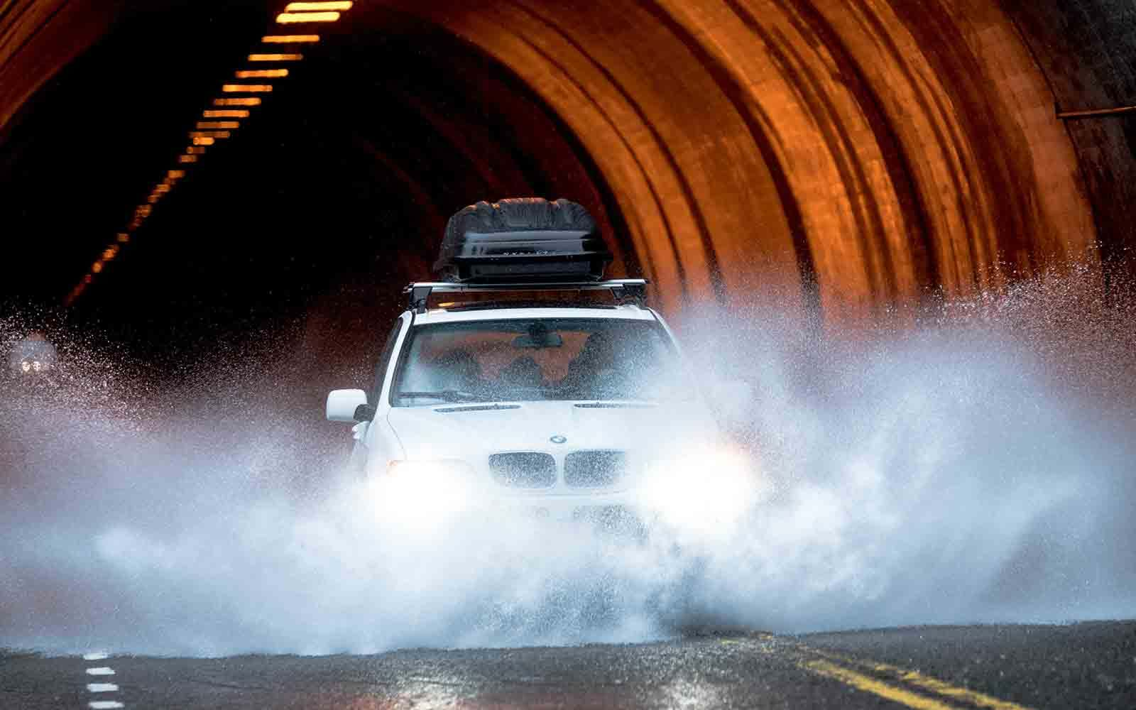 Car going through tunnel and splashing along water covered road