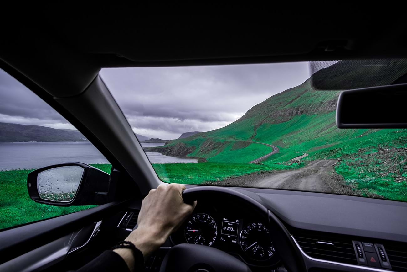 Car driving on winding dirt road on hillside