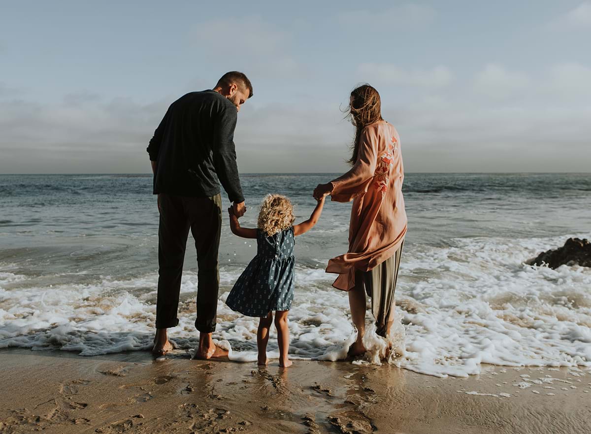 Parents and child standing in waves at beach