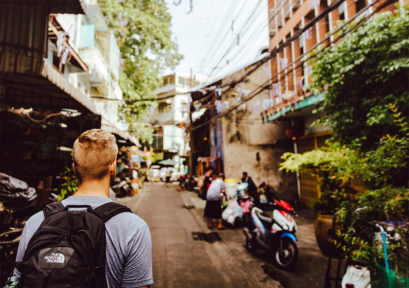 Young man walking through cluttered narrow street