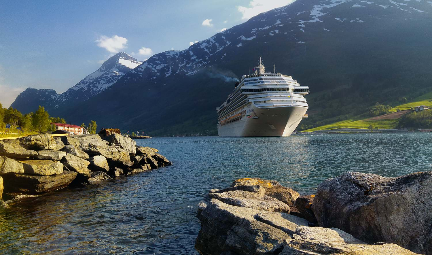 Cruise ship on river next to snowy mountain