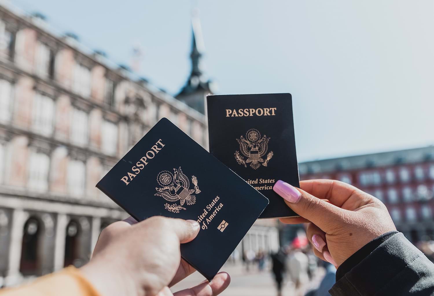 Two people holding passports in city courtyard