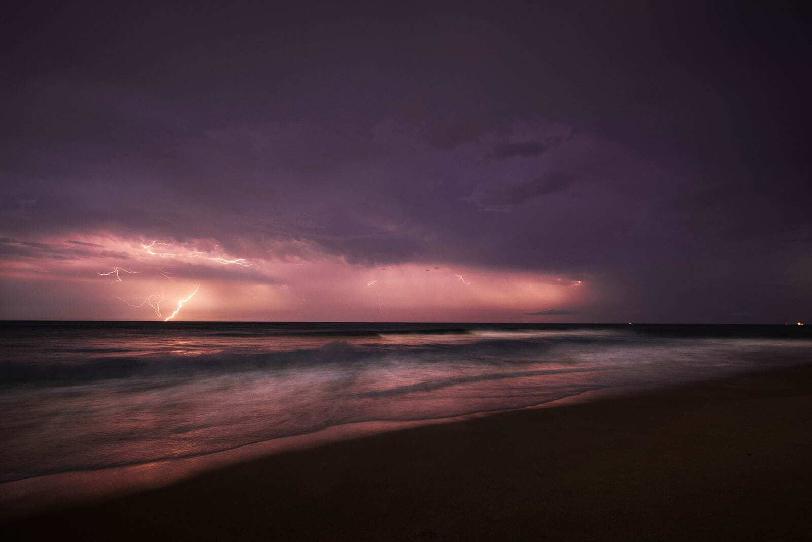 Lightning illuminating cloudy sky above ocean