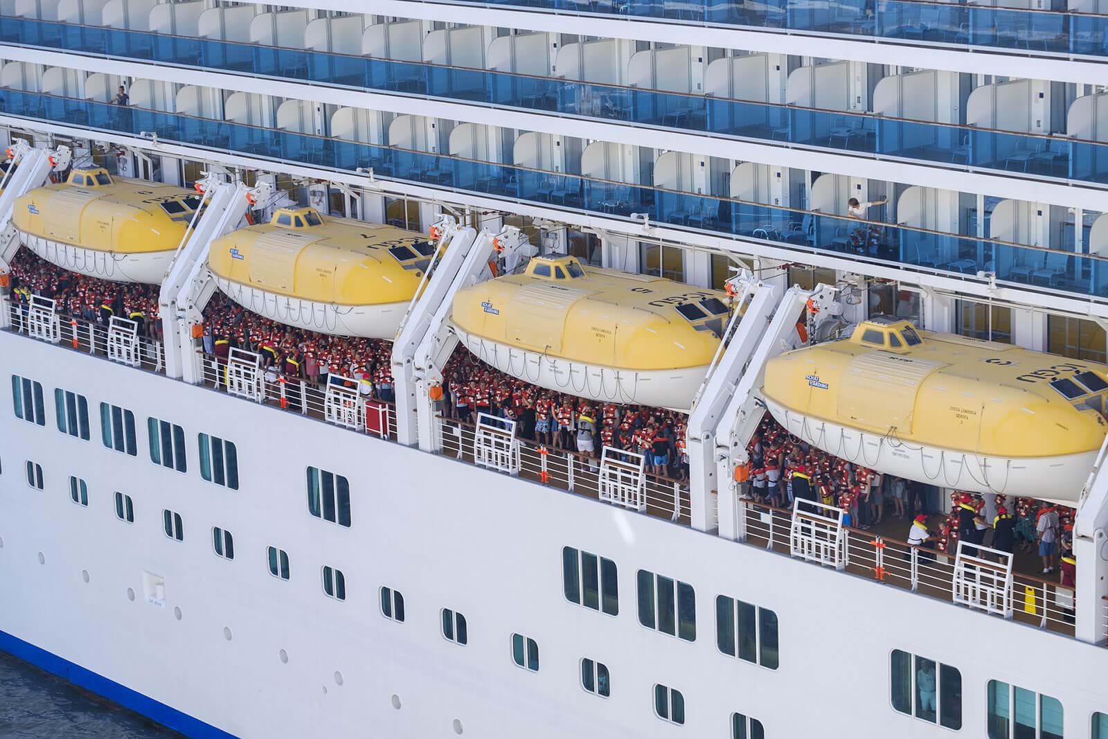 Passengers gathered around cruise ship lifeboats