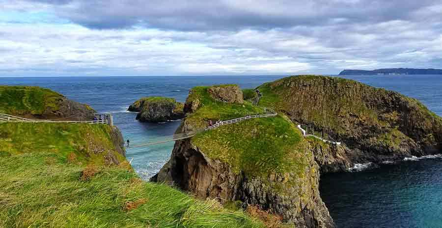 Person walking on bridge connecting cliffs in Ireland