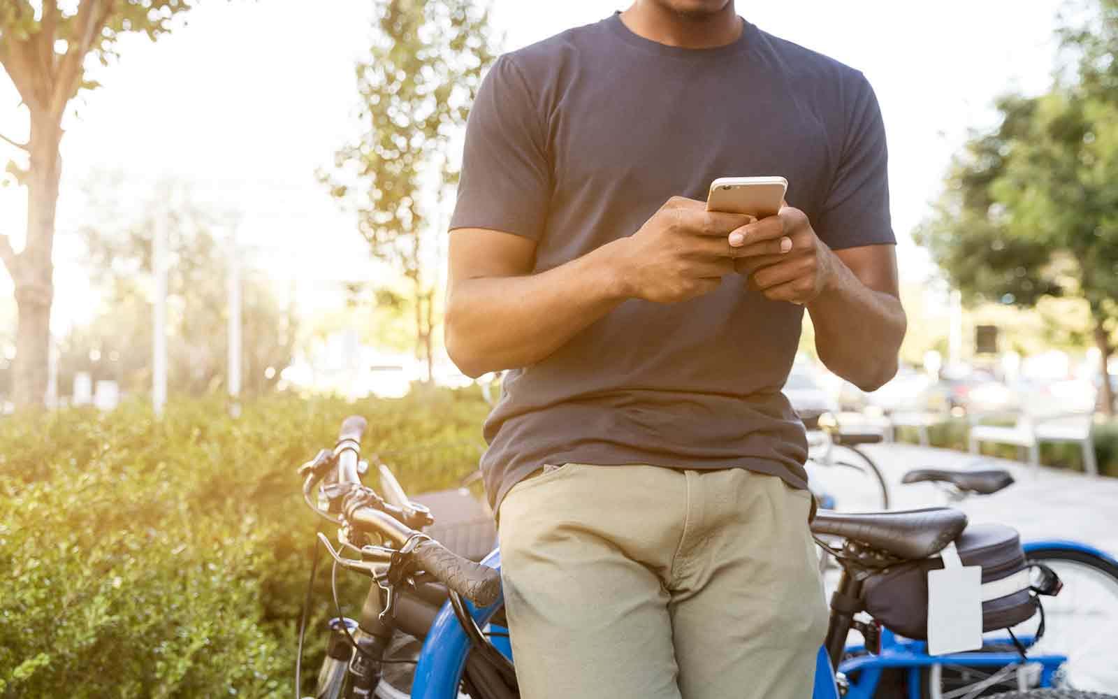 Person on their phone standing with their bike