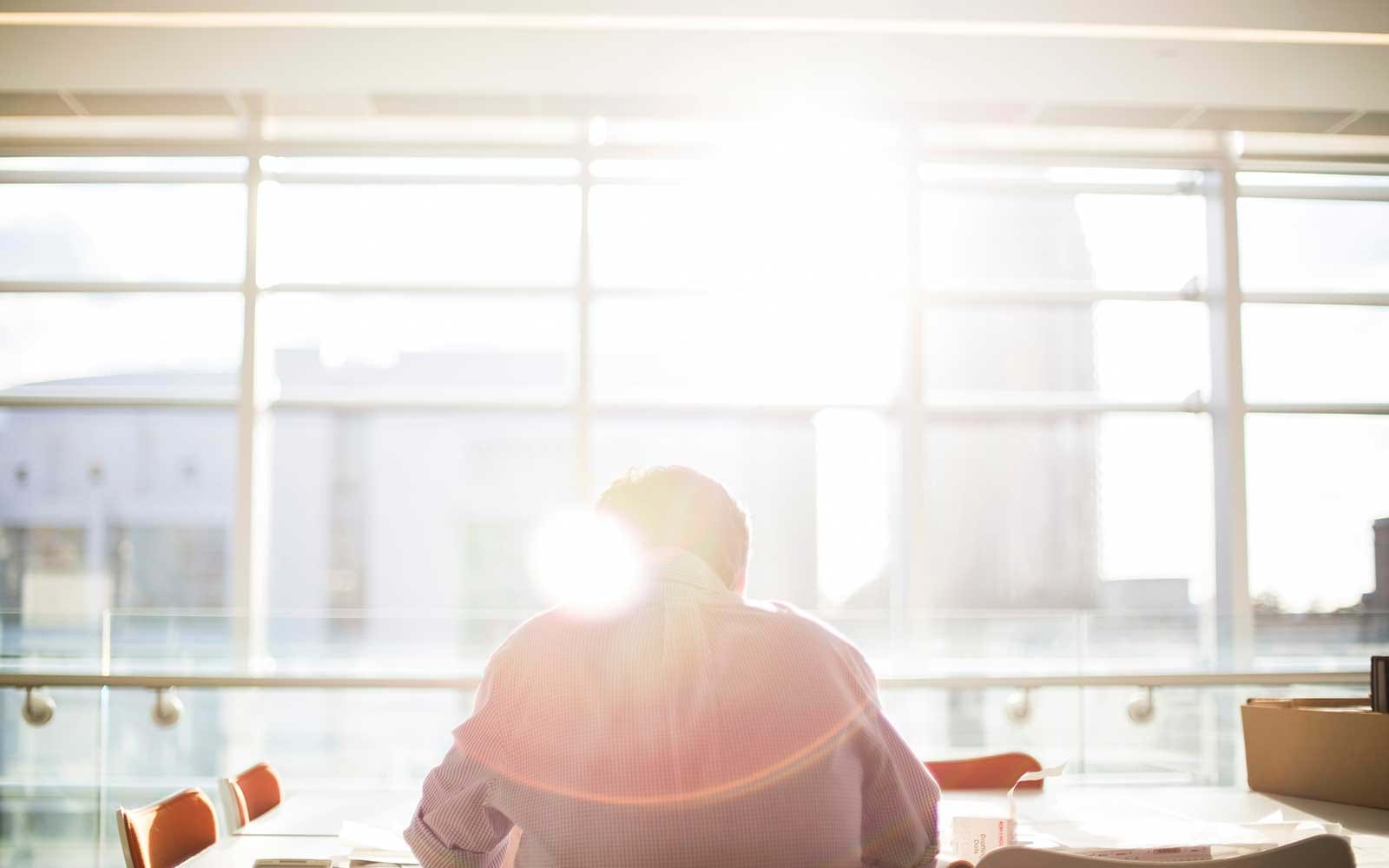 Person writing at a table in bright sunlight