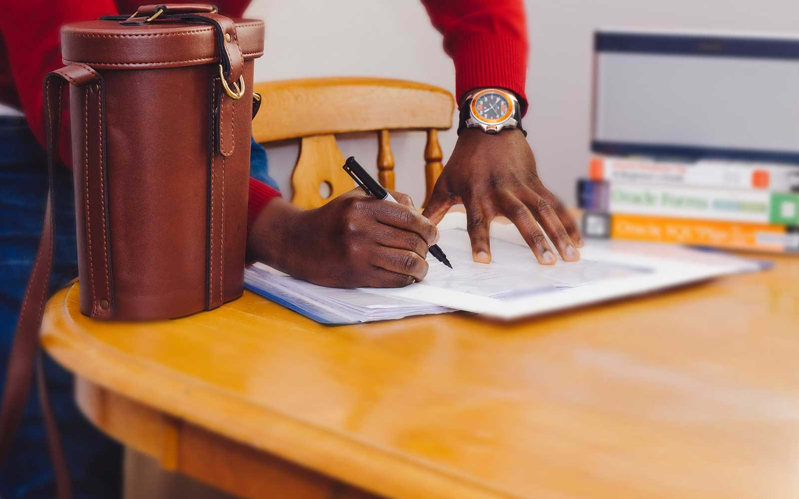 Person writing on documents on table