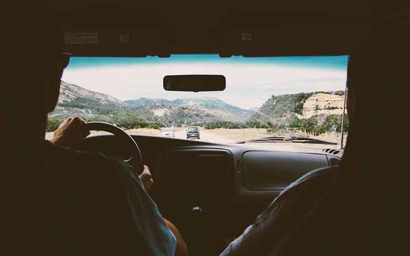 Two people driving down road through mountain landscape