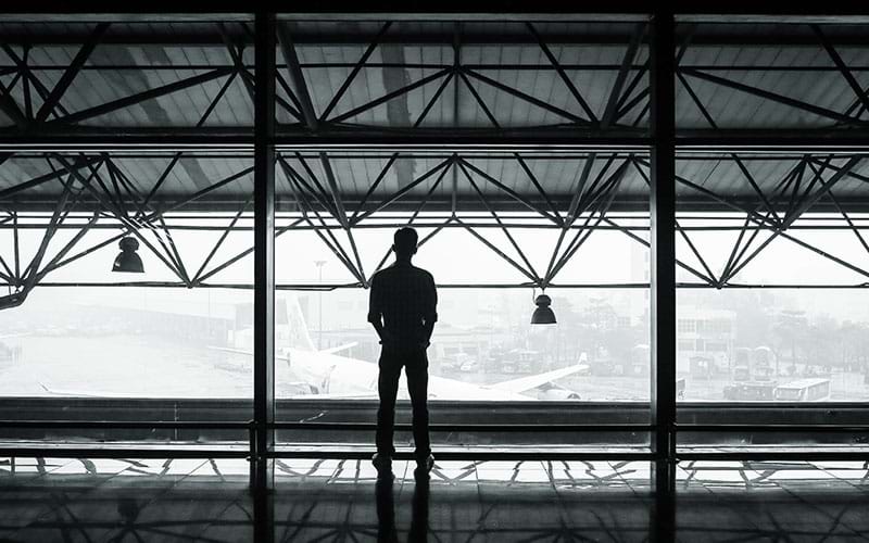 Person in airport looking out at plane