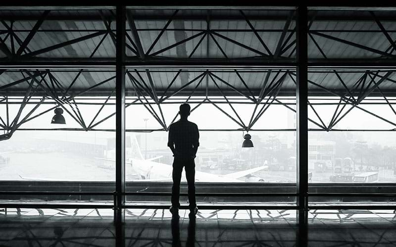 Person in airport looking out at plane