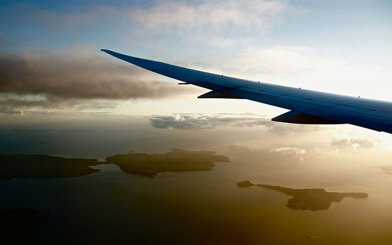 Airplane wing flying over ocean